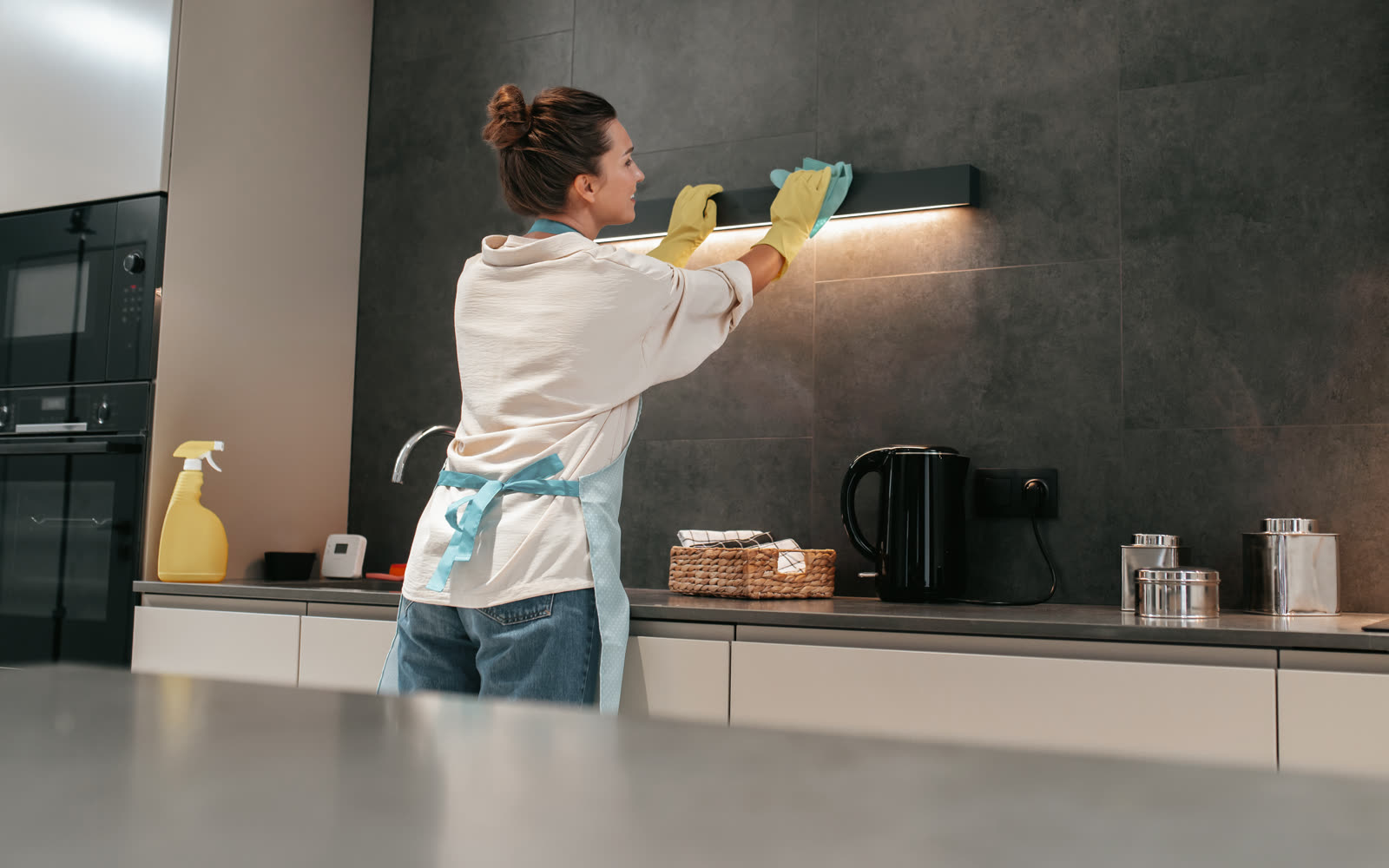 Cleaner wiping down kitchen surfaces before a handover